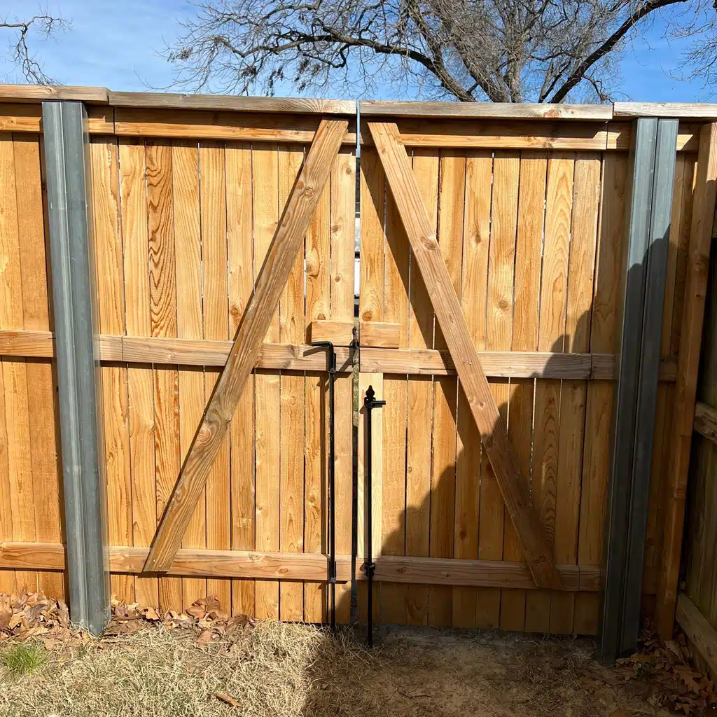 A custom wood gate with diagonal cross-bracing in a finished fence