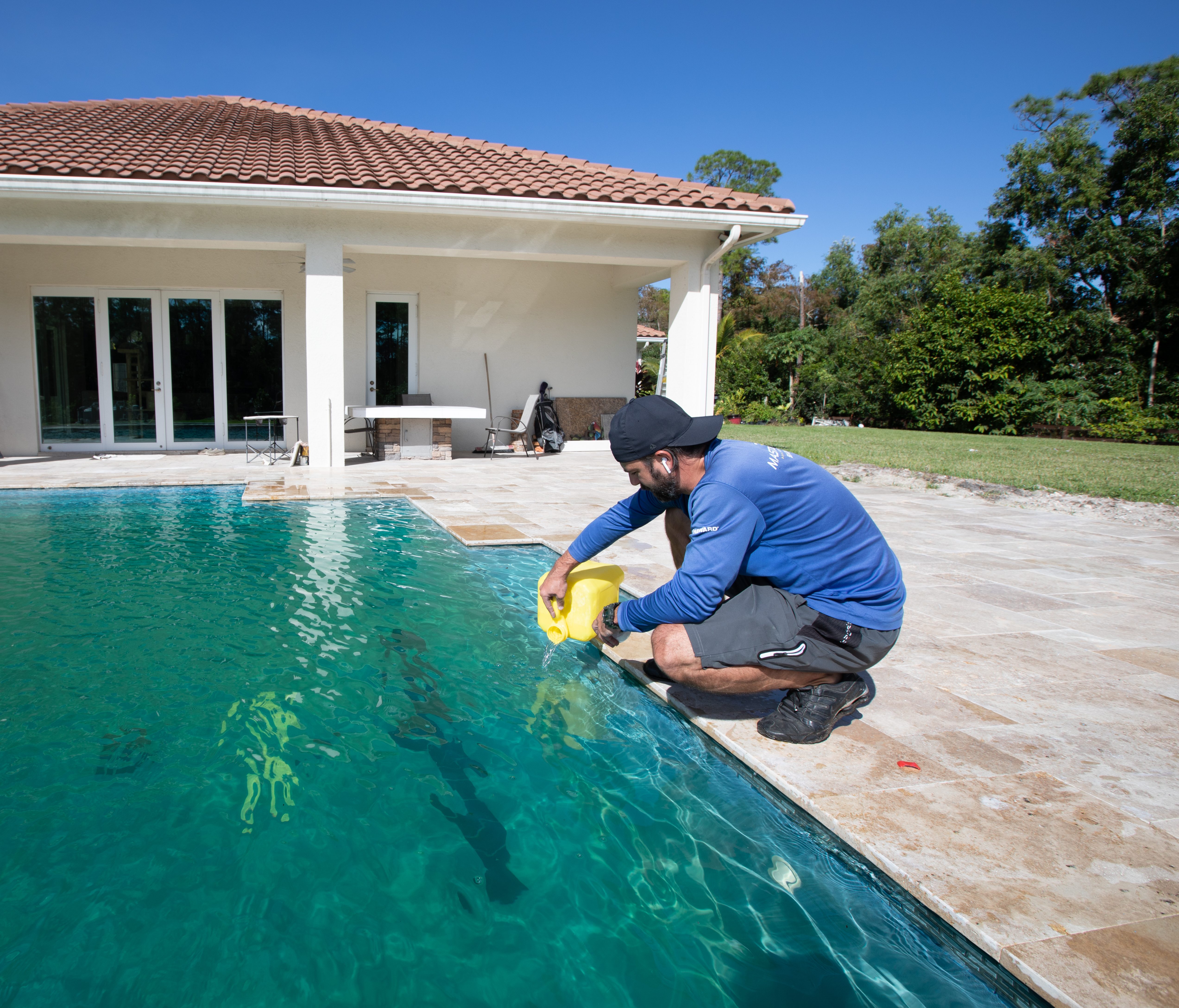 A Clearline pool tech treating a backyard pool poolside