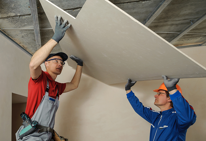 Two technicians installing drywall together
